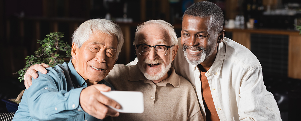 smiling asian man taking selfie on smartphone with senior multiethnic friends, banner